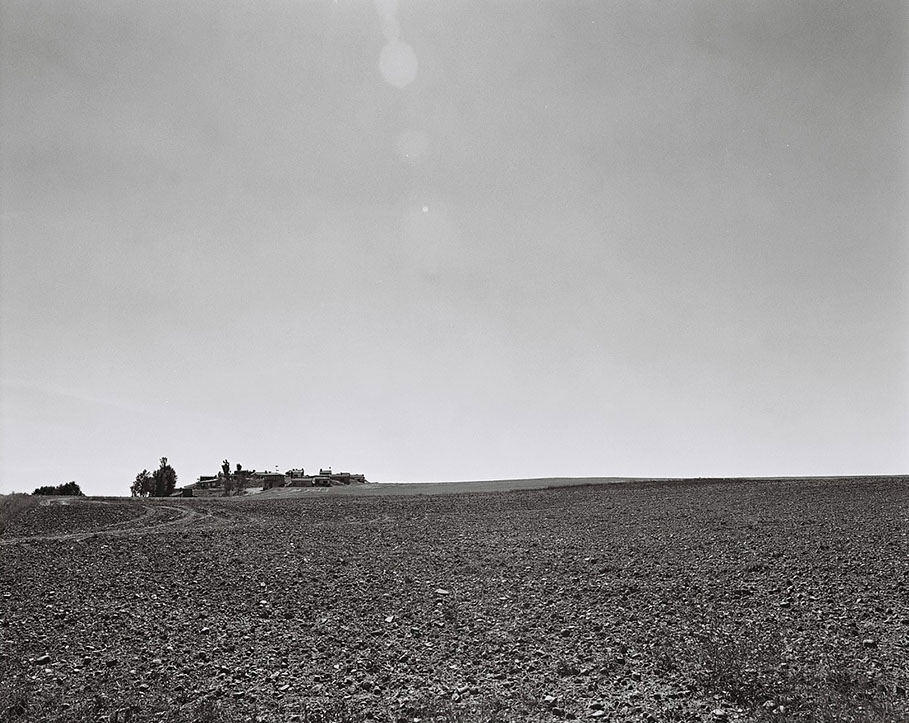 Paysage aride d'une champ en Castille y Leon, avec en fond quelques maisonnettes d'ouvriers agricoles