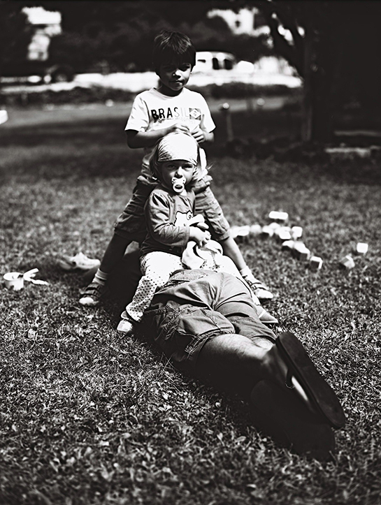 Portrait d'enfants d'amis jouant sur le dos du père de la petite fille, qui lui essaie de faire la sieste