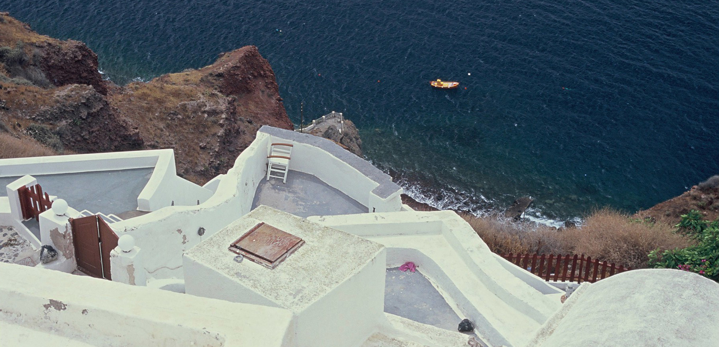 Vue de la Caldera de Santotin, où vogue une barque de pêcheur, depuis une maison cycladique d'Oia