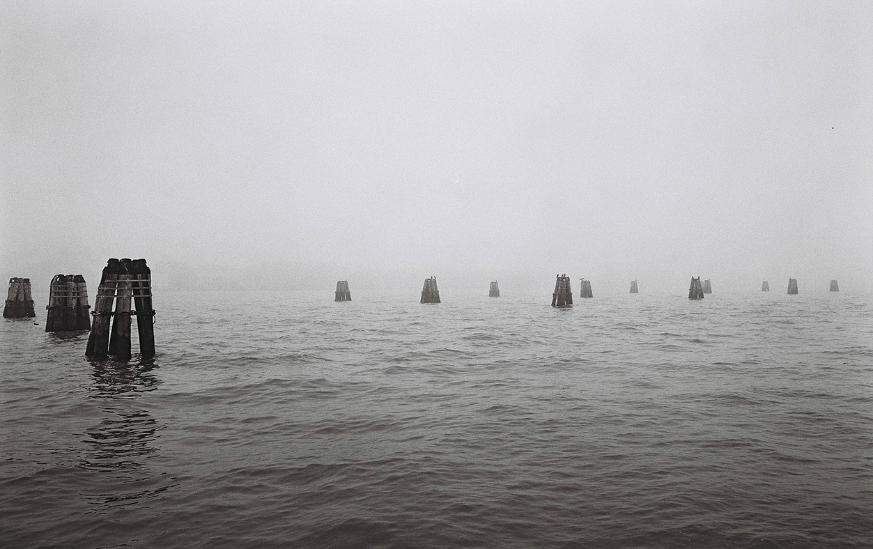 Photographie de rue montrant un matelas et quelques affaires appartenant à un SDF à Lyon, avec en perspective 2 hommes de dos discutant